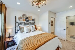 Un dormitorio ordenado con cama, mesitas de noche, cabecero de pared y una puerta.