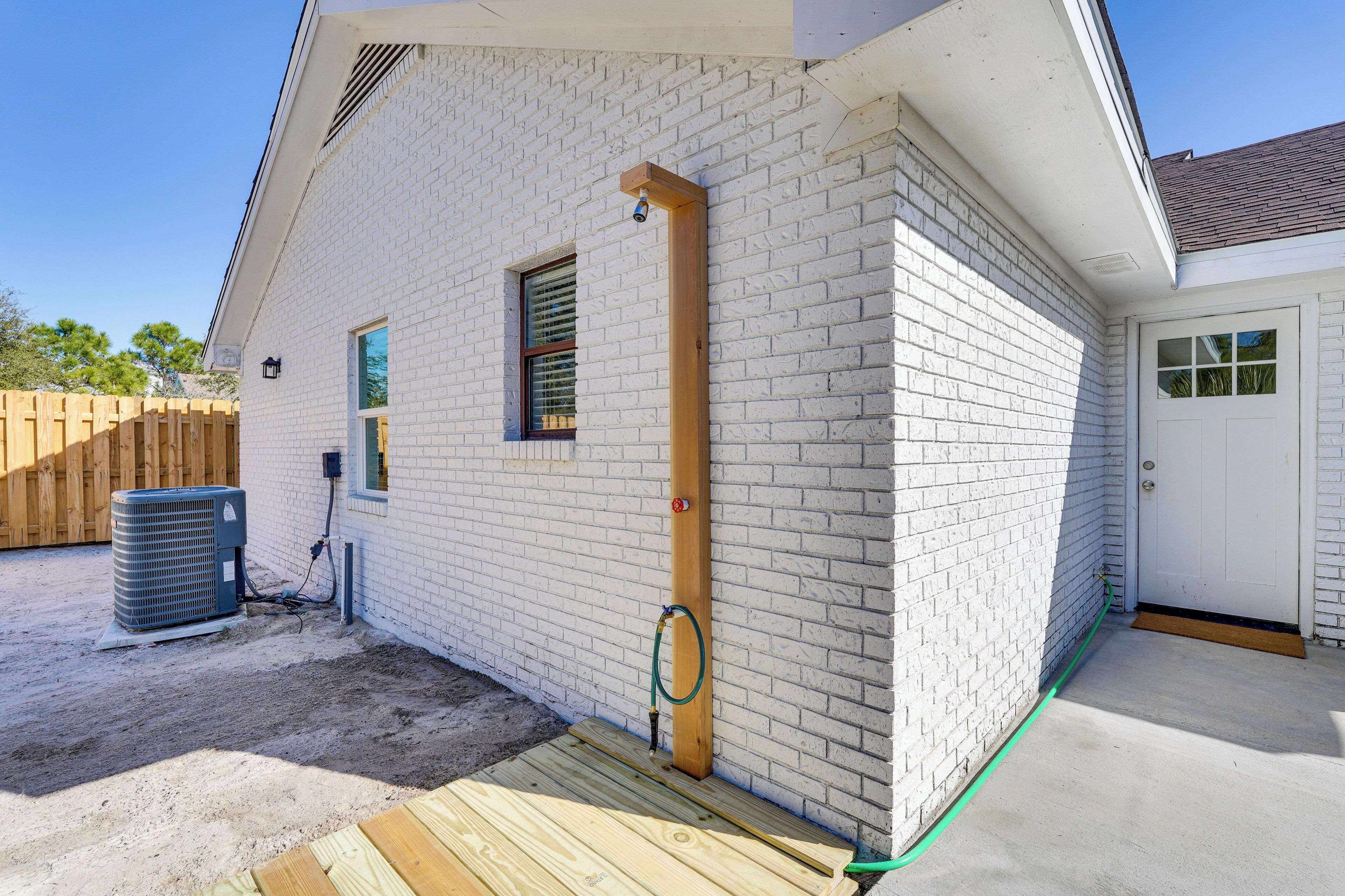 A white brick house with a wooden deck, a door, and a window.