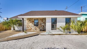 A single-story house with a stone facade, a tiled roof, and a gravel driveway. - Panama City Beach House w/ Patio, Walk to Ocean (Panama City Beach)