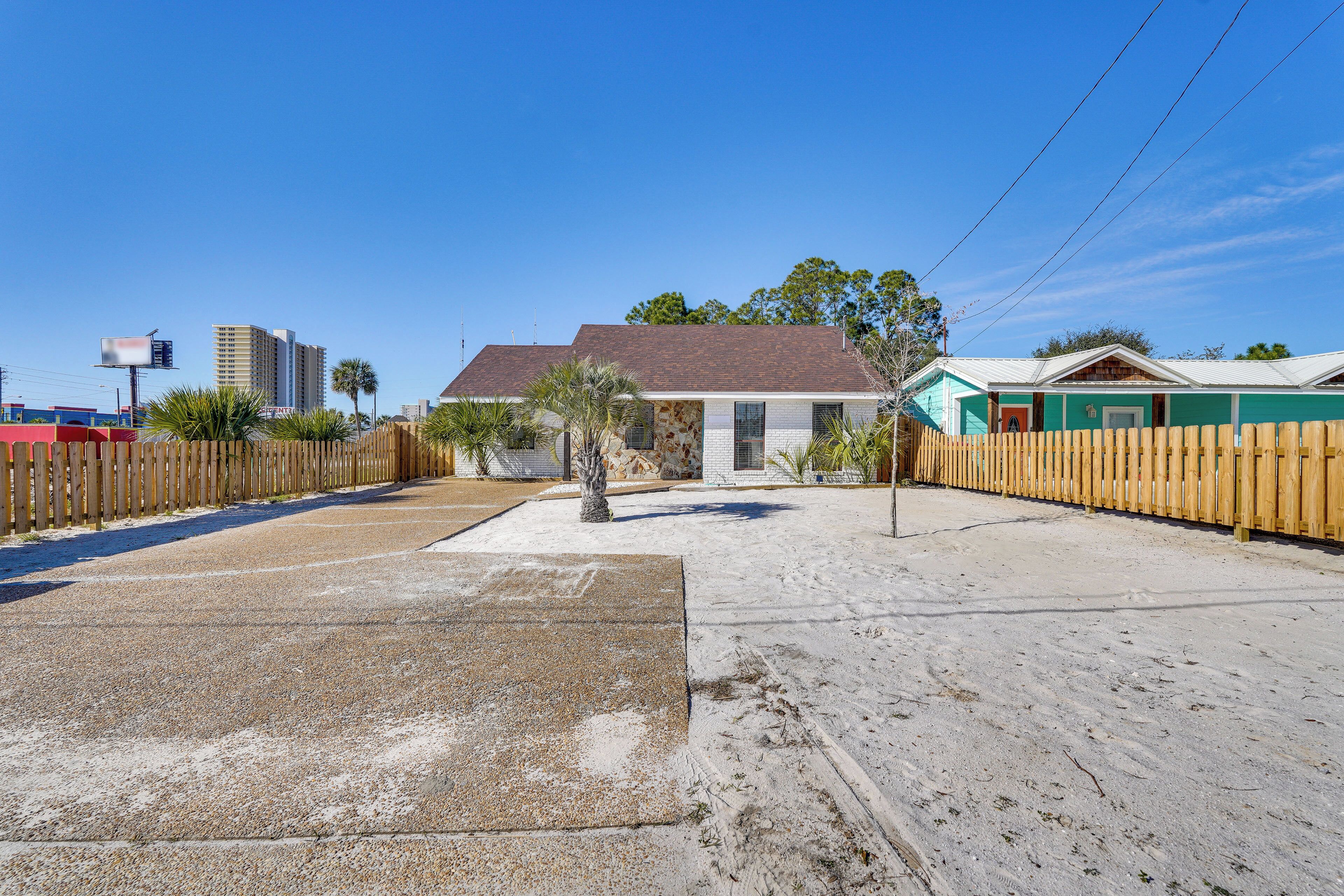 A beachfront property with a sandy area, a wooden fence, and a building with a tiled roof.