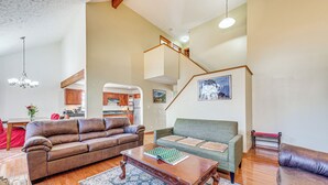 A spacious living room with a brown leather sofa, a green sofa, and a wooden coffee table. There is a staircase leading to an upper level. - 11 Mi to Camelback Resort: Tobyhanna Home! (Tobyhanna)