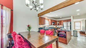 A modern kitchen with wooden cabinets, a stainless steel refrigerator, and a dining area with a wooden table and chairs. - 11 Mi to Camelback Resort: Tobyhanna Home! (Tobyhanna)