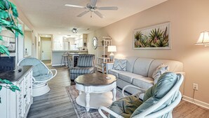 A living room with a sofa, chairs, a coffee table, and a ceiling fan. - Pawleys Island Condo w/ Screened Porch + Golfing! (Pawleys Island)