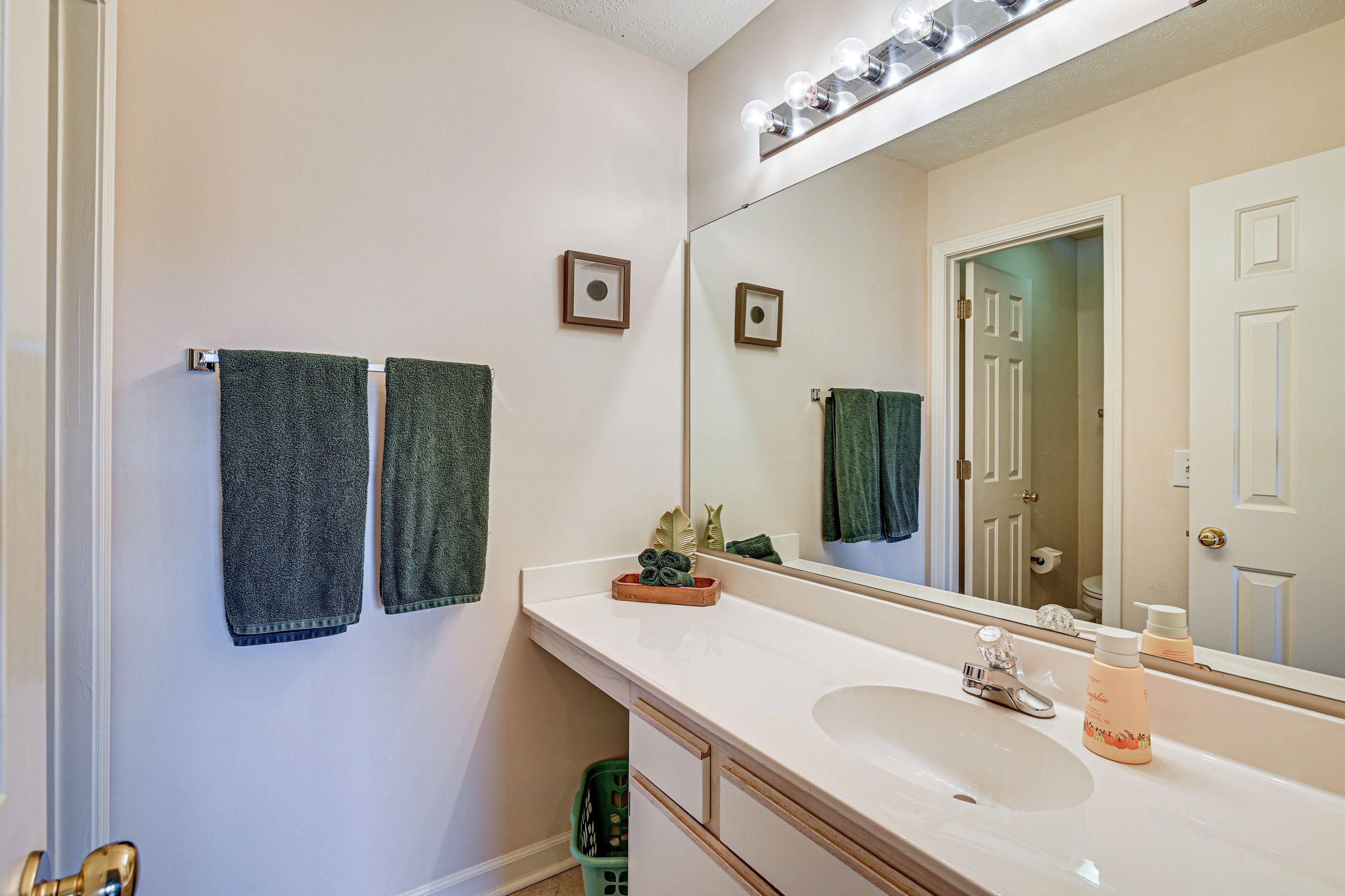 A bathroom with a white sink, a mirror, and two towels hanging on the wall.