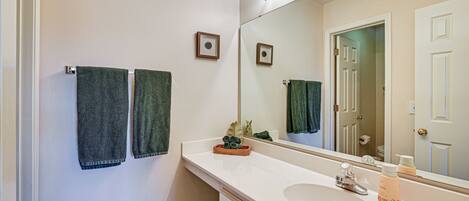 A bathroom with a white sink, a mirror, and two towels hanging on the wall.