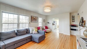 Un salón espacioso con un sofá modular gris, una mesita blanca y suelo de madera.