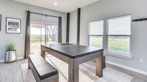 A ping pong table in a room with large windows, a bench, and a potted plant. - Modern Farmhouse in Del Valle: Rural Setting! (Del Valle)
