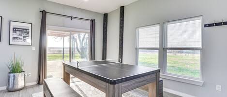 A ping pong table in a room with large windows, a bench, and a potted plant.