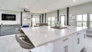 A spacious kitchen with a large island, white cabinetry, and a ceiling fan. - Modern Farmhouse in Del Valle: Rural Setting! (Del Valle)