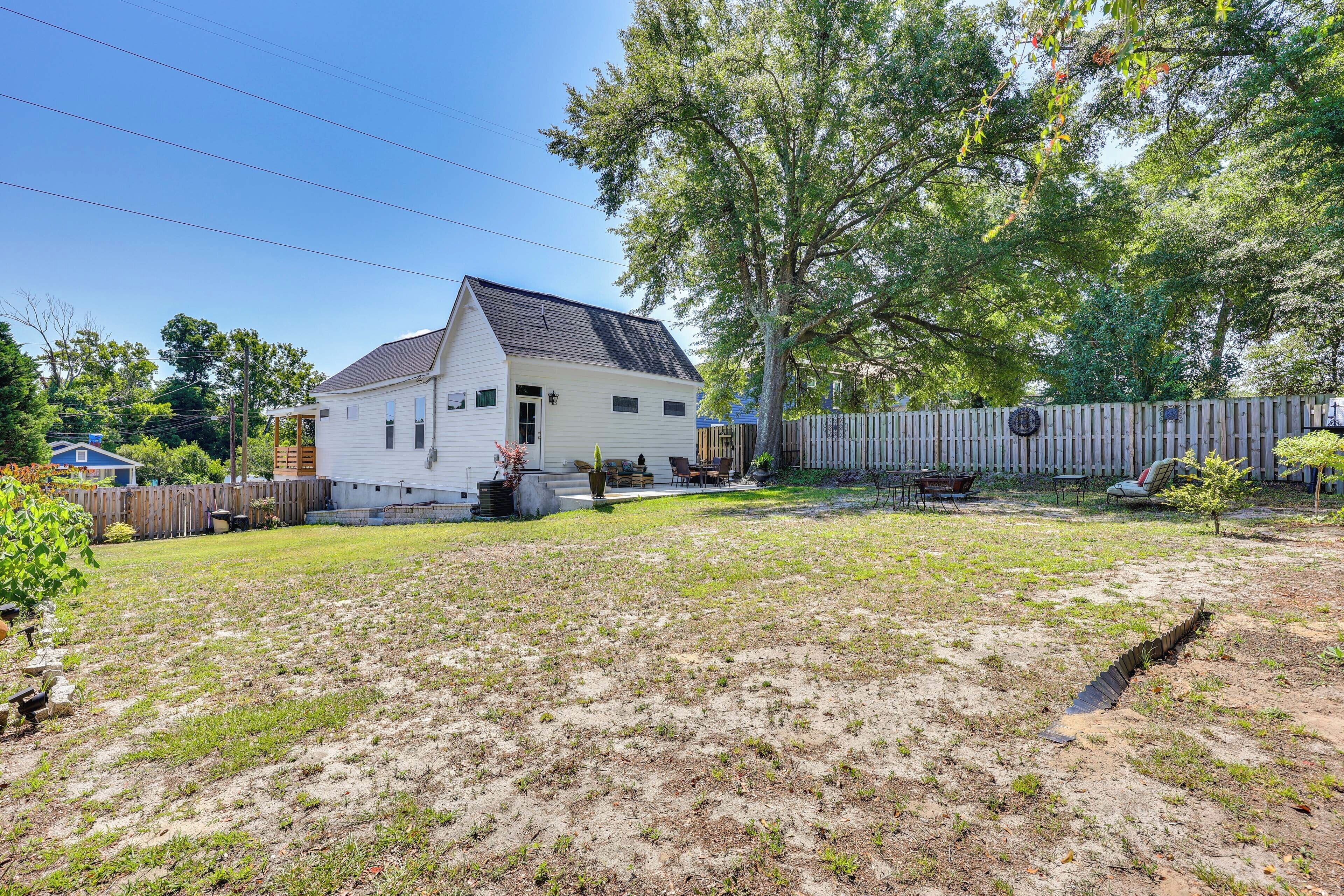 A single-story house with a sloped roof, a fenced backyard, and a wooden deck.