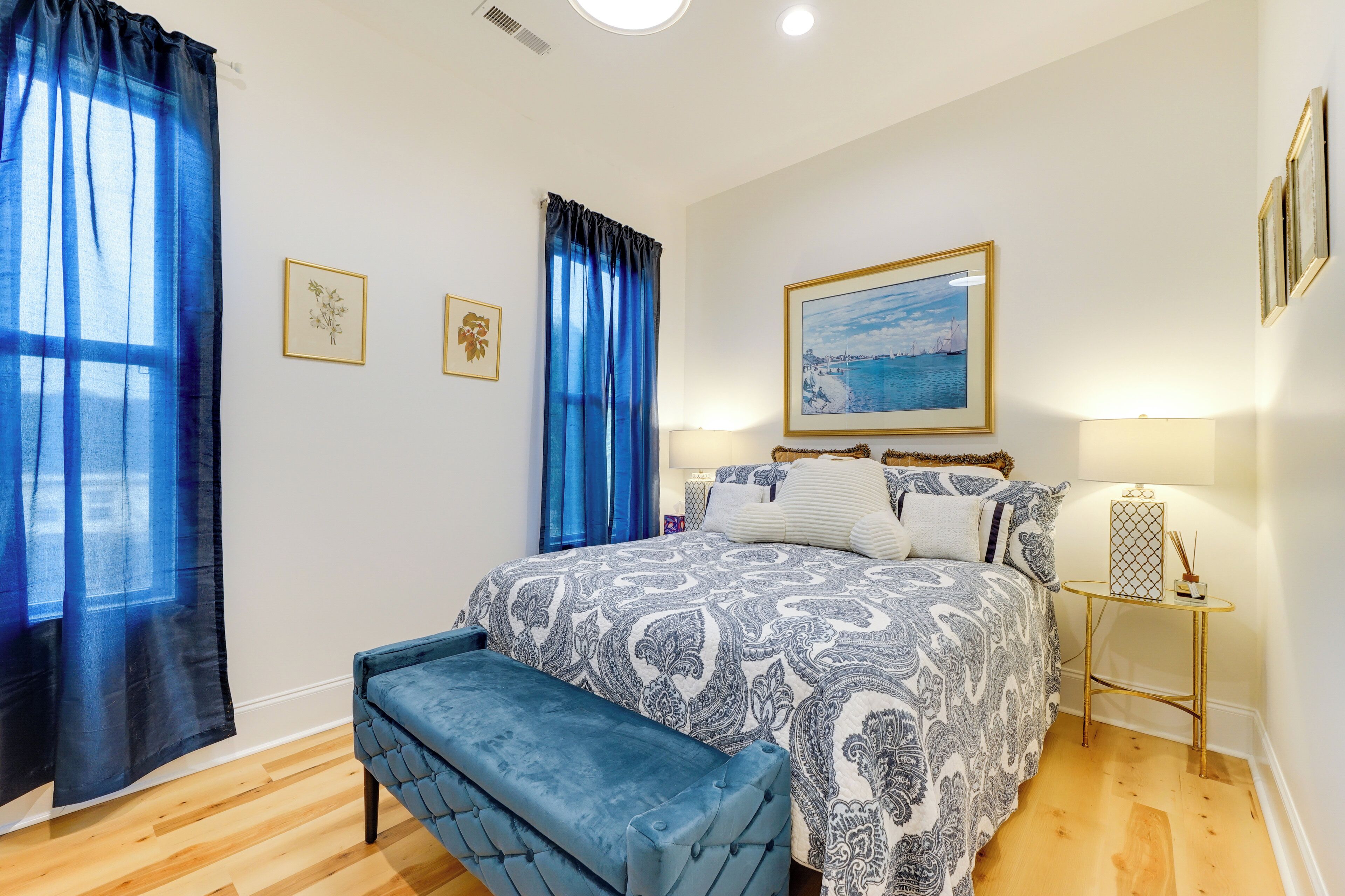 A bedroom with a bed, a bench, a bedside table, and a framed picture on the wall.