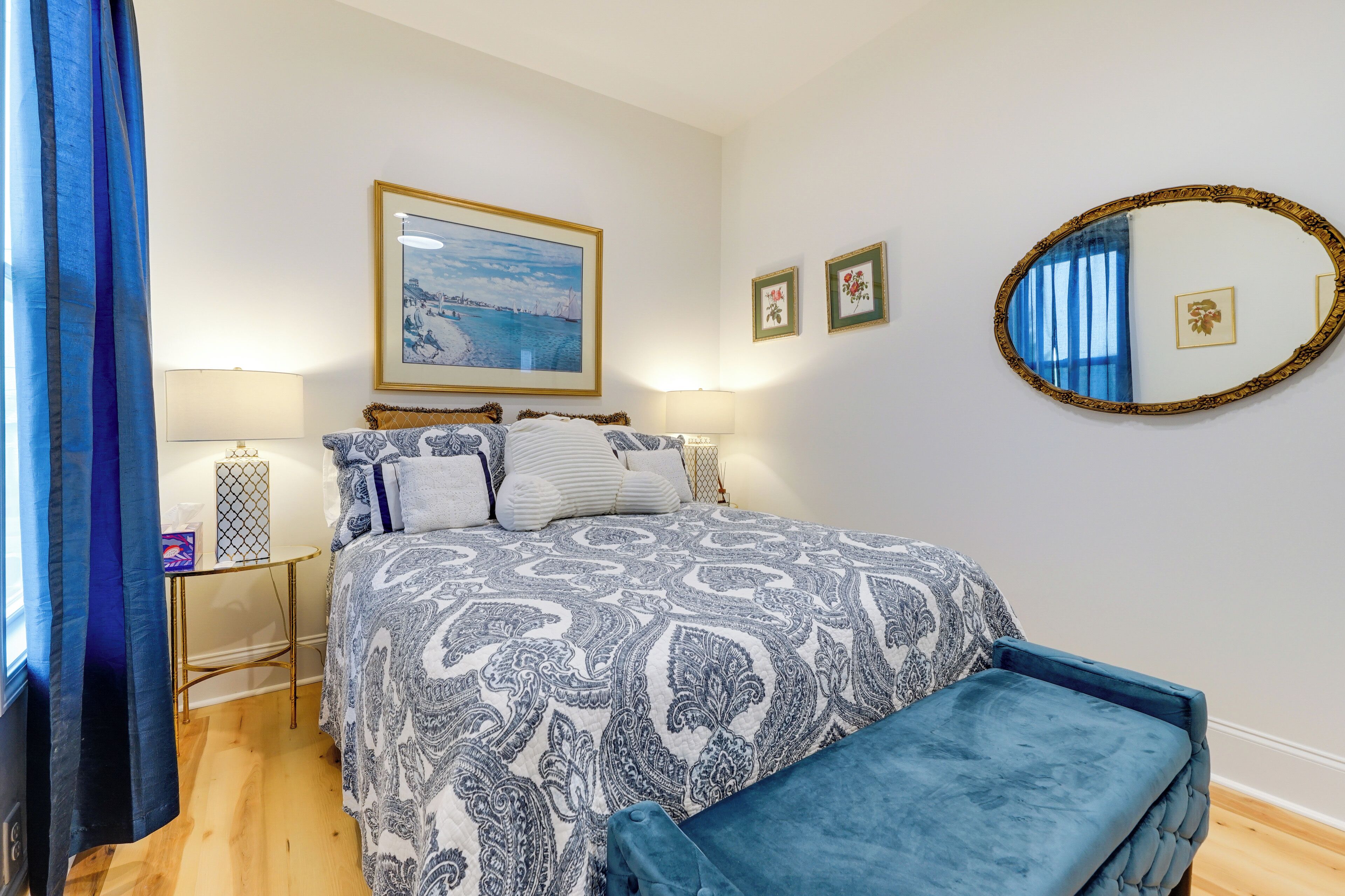 A bedroom with a bed, bedside tables, a mirror, and a window with curtains.