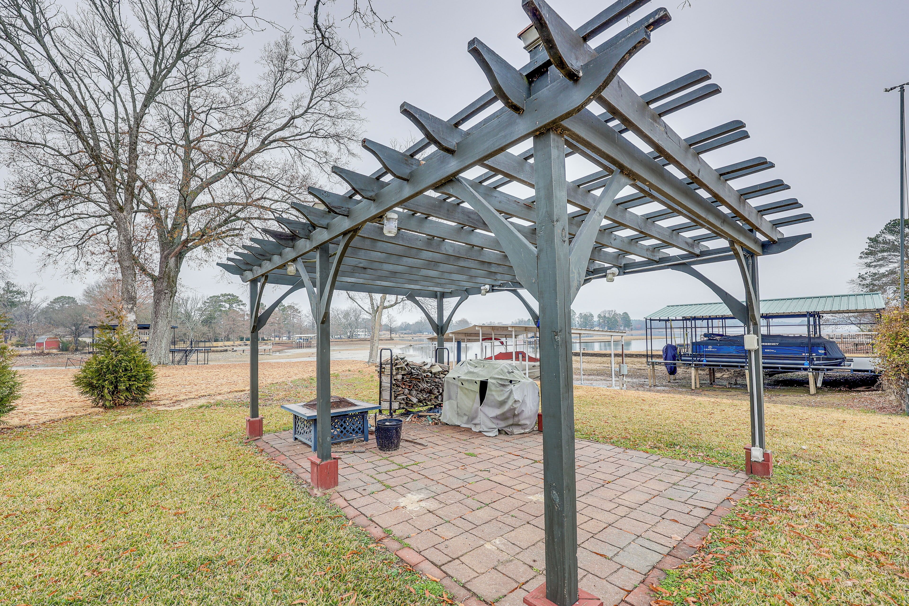 A covered outdoor area with a metal structure, a small tree, and a bench.