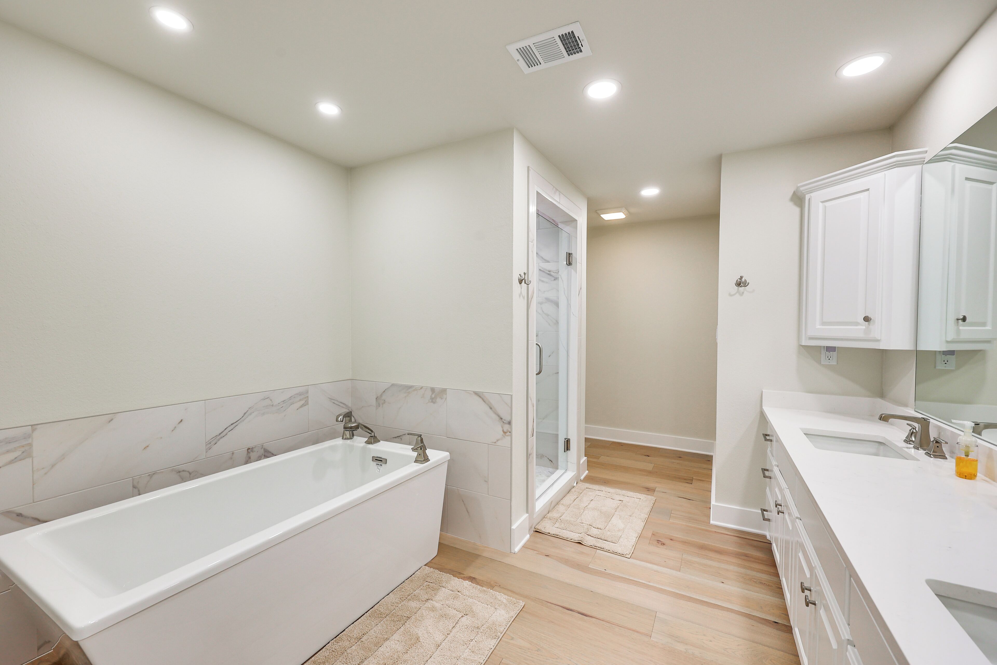 A modern bathroom with a large bathtub, a walk-in shower, and a vanity with a mirror.