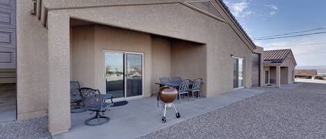 A building with a covered patio area, outdoor seating, and a barbecue grill.