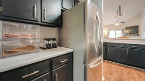 A modern kitchen with dark cabinets, a stainless steel refrigerator, and a built-in oven.