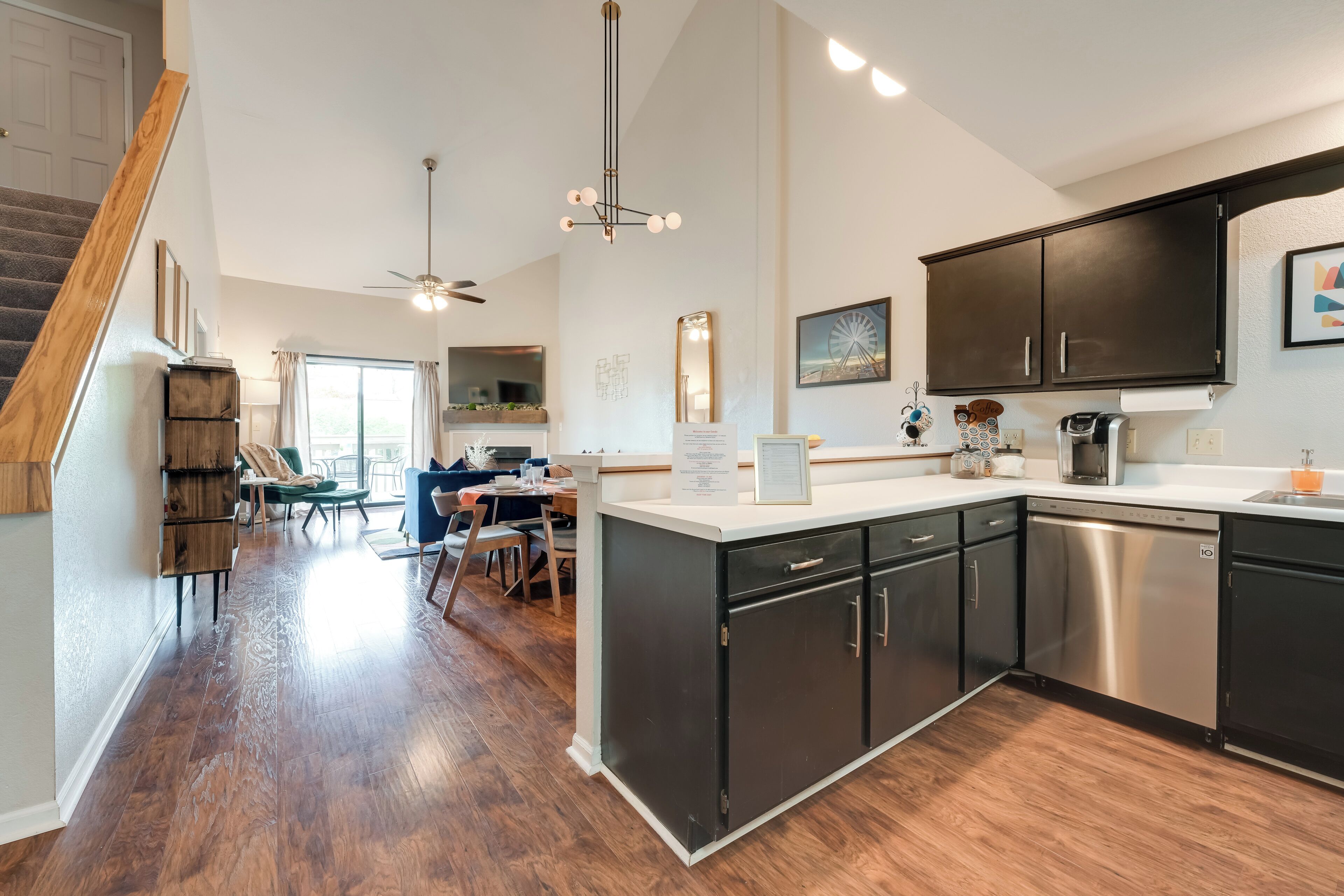 A modern kitchen with dark cabinets, a stainless steel dishwasher, and a dining area with a table and chairs.