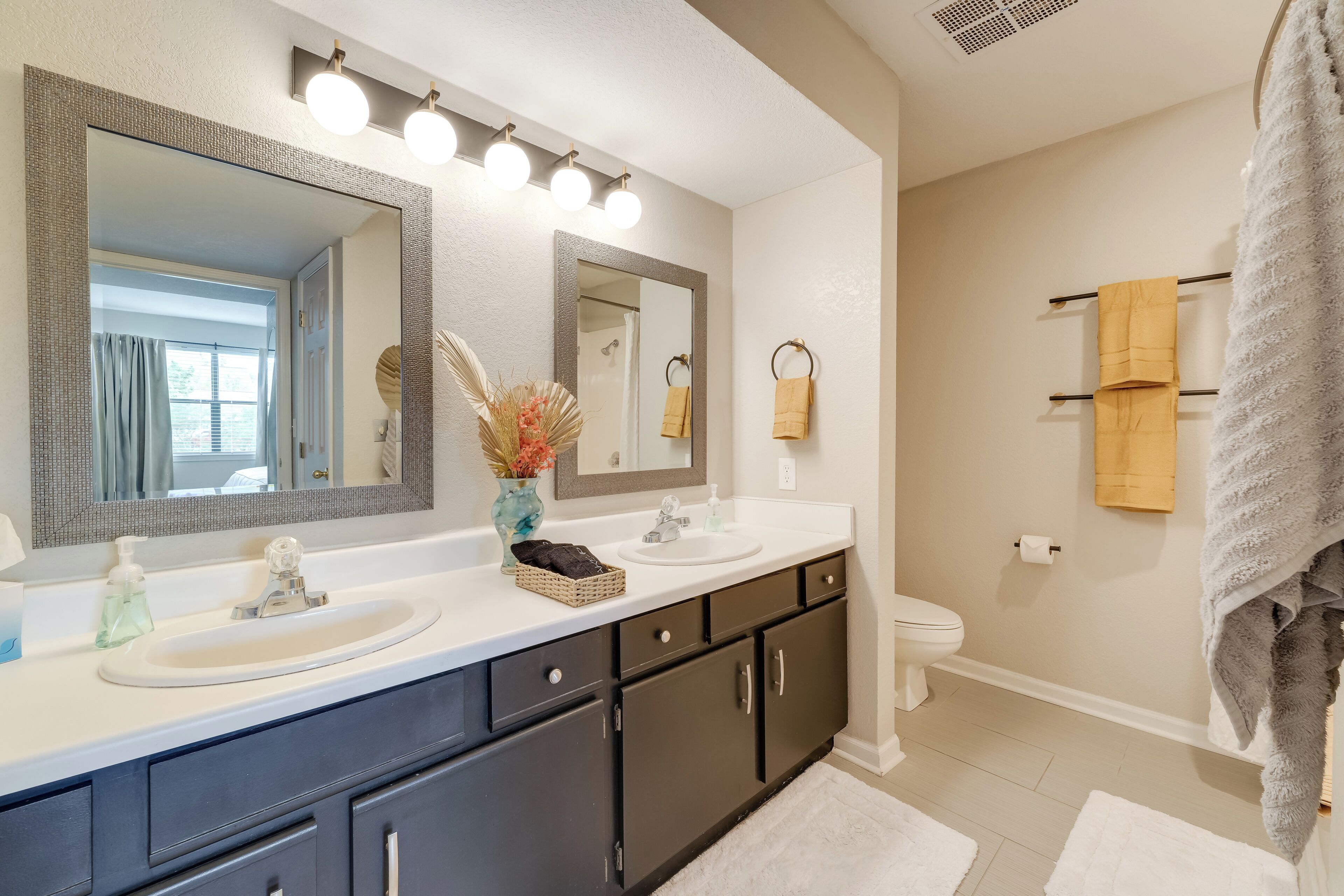 Une salle de bain avec un grand miroir, un meuble-lavabo et un porte-serviettes.
