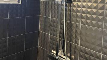 A shower with a curved hose and a handheld showerhead, set against a geometric patterned wall.