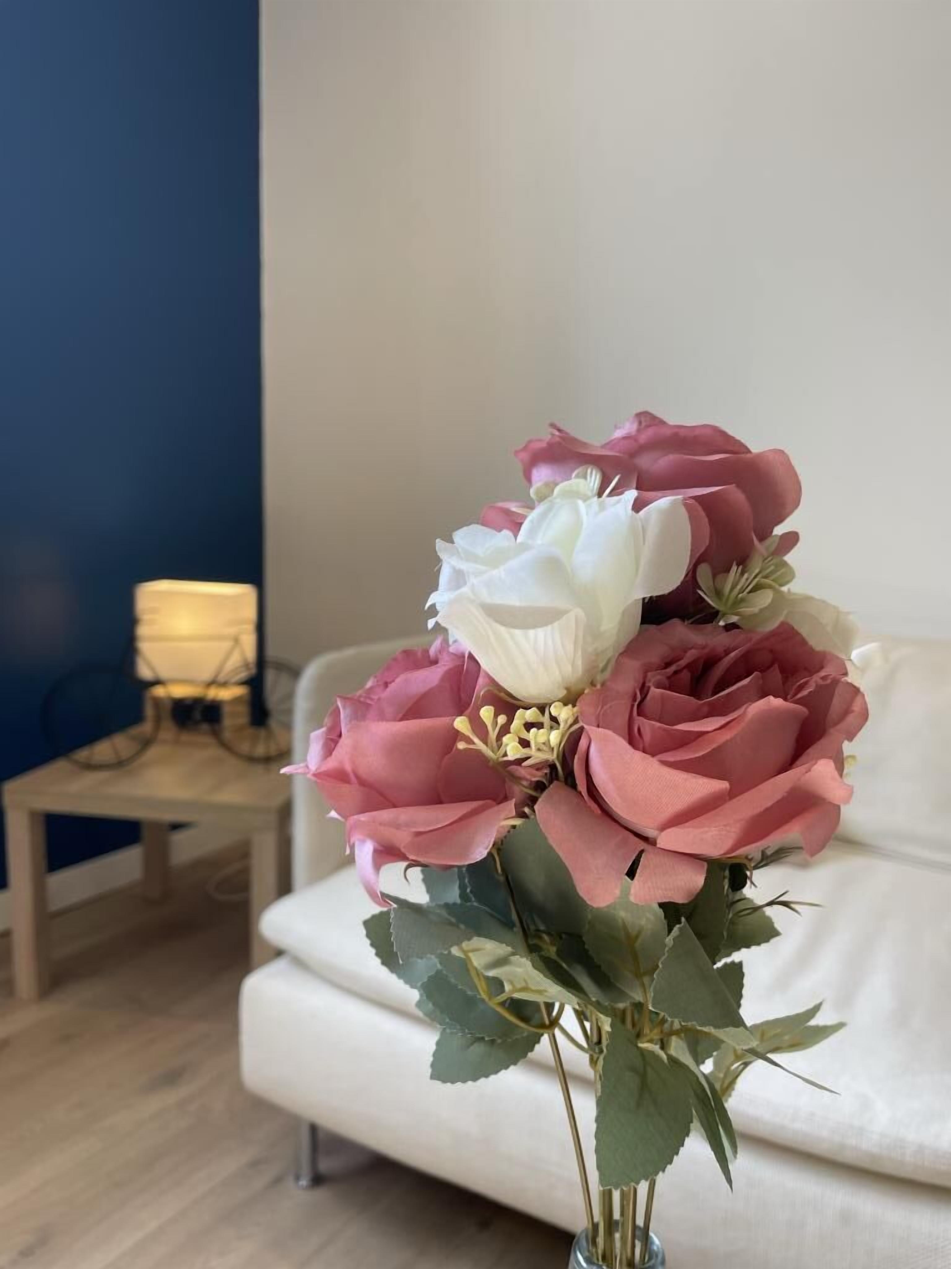 Een bloemenboeket in een vaas op een witte bank.