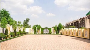 A spacious courtyard with patterned flooring, a central fountain, and a building with a green roof in the background. - SPARSH CANOPY RESORT (Jaipur)