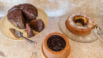Um bolo de chocolate com confeitos em um prato, um bolo bundt em um suporte de vidro e um bolo de chocolate em uma tigela de madeira.