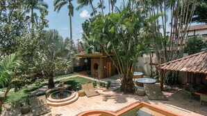 A courtyard with a swimming pool, lounge chairs, a small wooden structure, and tropical plants. - Pousada Pazuu (Ubatuba)