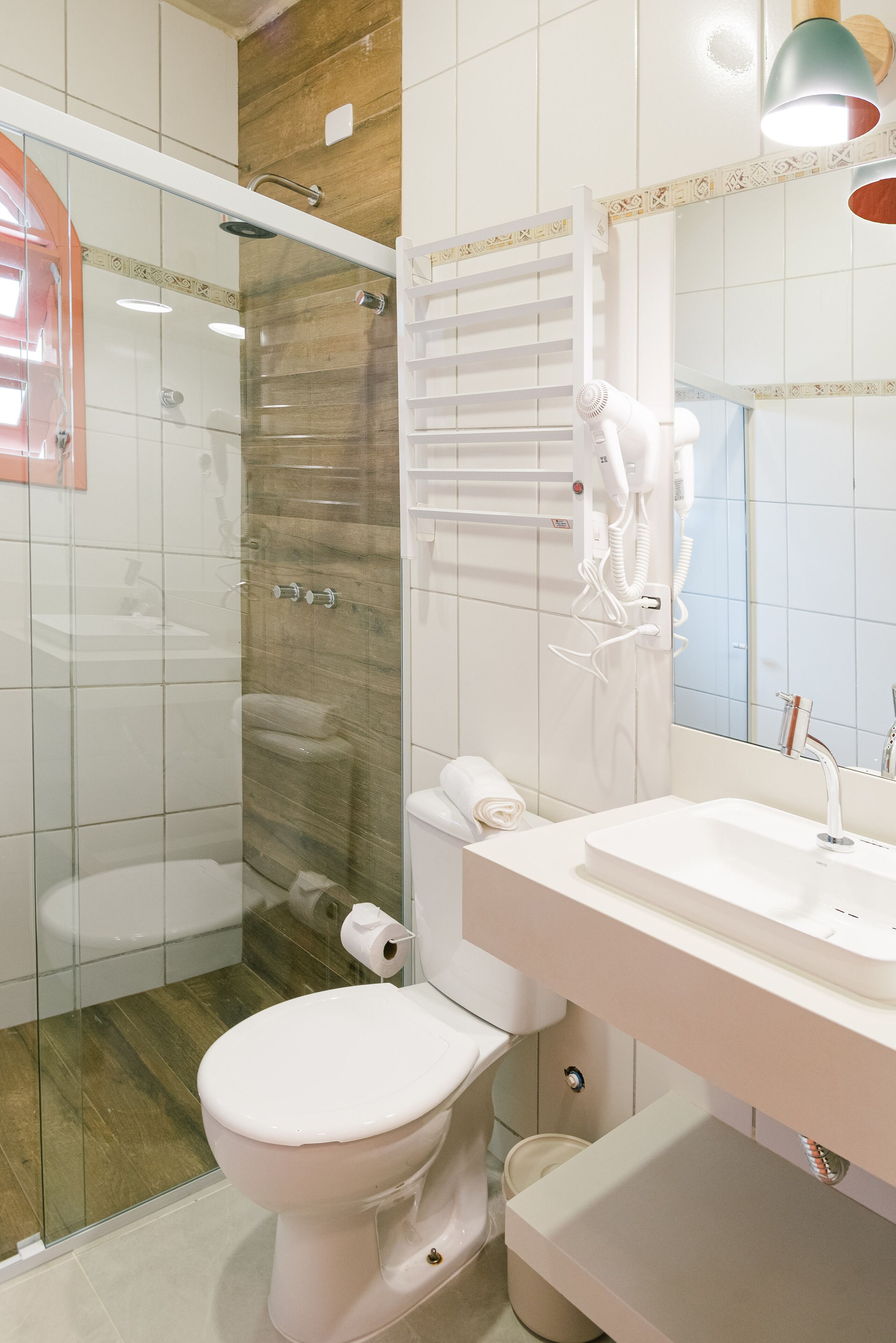 Un baño moderno con ducha de vidrio, inodoro blanco y tocador con espejo.