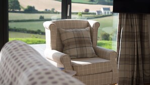 A room with a view of rolling hills and a chair with a plaid cushion.