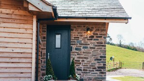 A wooden cabin with a dark door, stone walls, and a small porch with potted plants.
