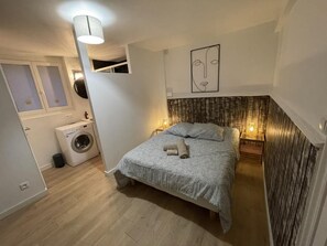 Ein Schlafzimmer mit einem Bett, einer Waschmaschine, einem Wandbild und einem hölzernen Kopfteil.