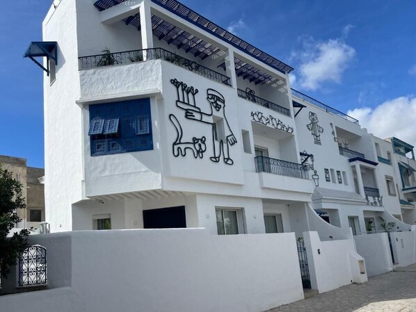 Un edificio blanco con balcones y una puerta azul.