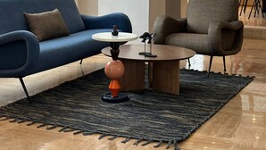 Ein modernes Wohnzimmer mit einem blauen Sofa, einem grauen Sessel und einem runden Couchtisch.