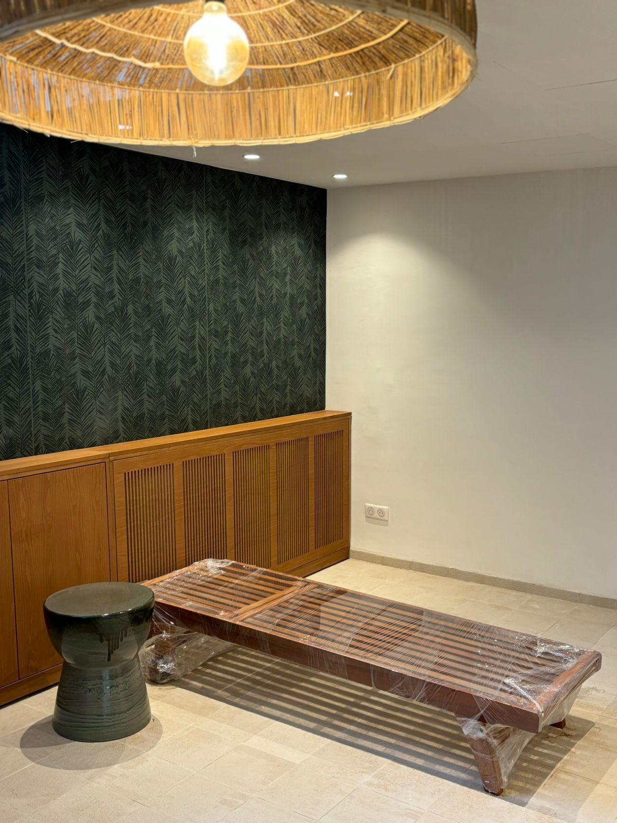 Una habitación con un banco de madera, una mesa redonda y una pared con diseño.