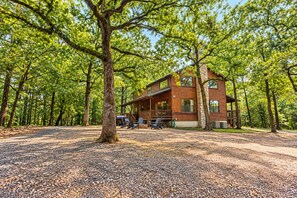 A cabin with a porch, surrounded by trees. - Bison Point, Smoker Grill, Corn Hole, Fire Pit, Game Table, Ladder Ball (Broken Bow)
