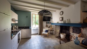A kitchen with a built-in oven, a dining area with a table and chairs, a fireplace, and a television mounted on the wall.