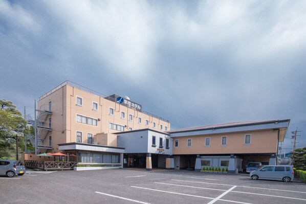 A multi-story hotel with a parking lot, a covered entrance, and a sign indicating a restaurant on the ground floor.