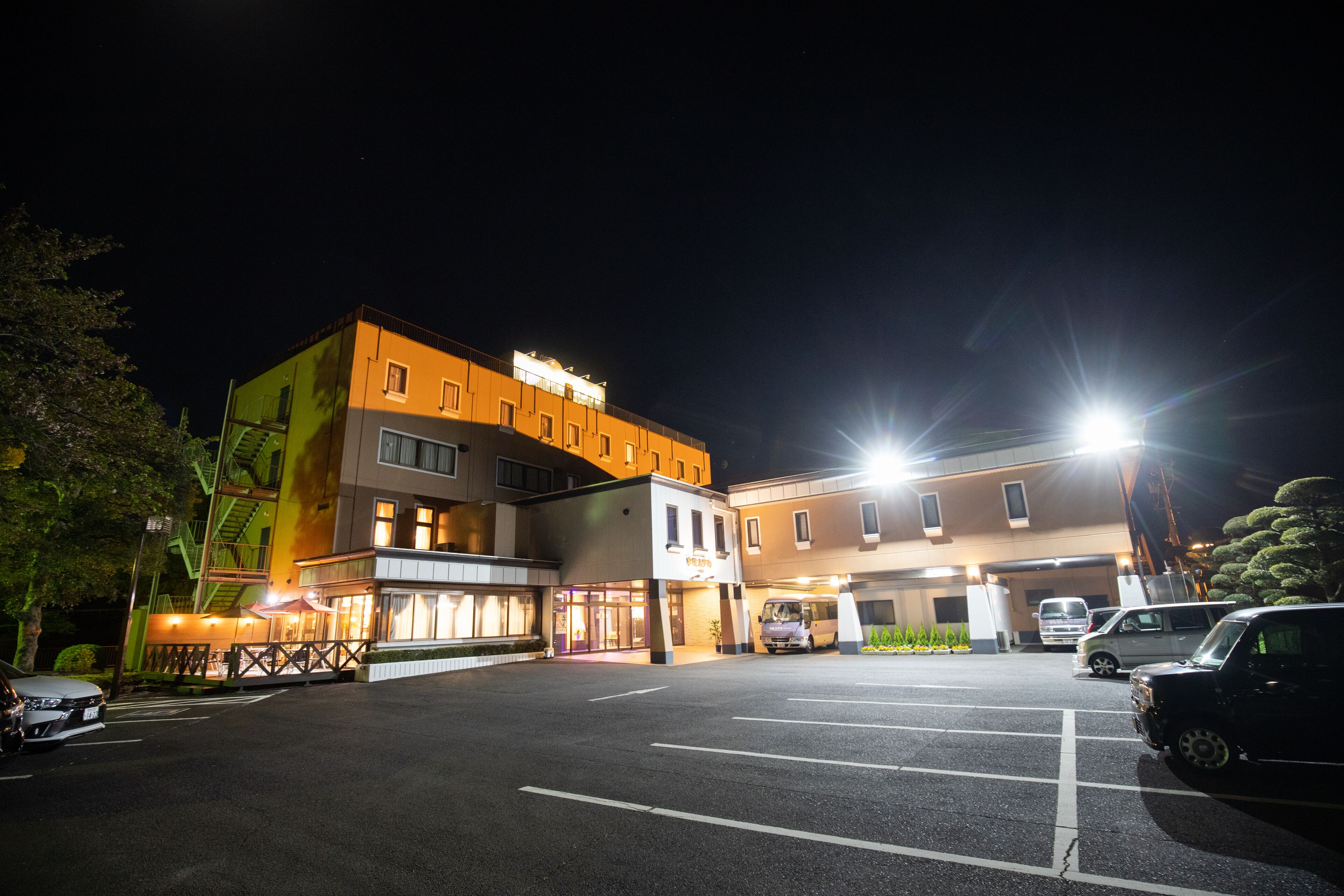 A multi-story hotel with a parking lot, a restaurant, and a building with a sign.
