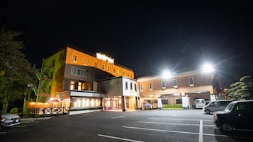 A multi-story hotel with a parking lot, a restaurant, and a building with a sign.
