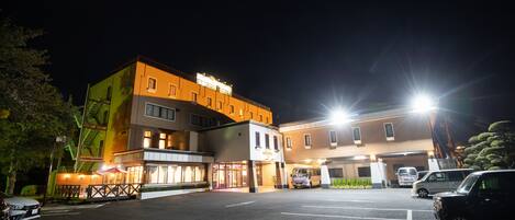 A multi-story hotel with a parking lot, a restaurant, and a building with a sign.