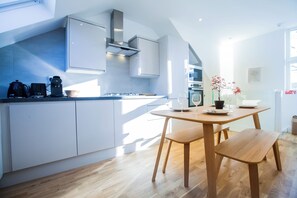 Una cocina moderna con armarios blancos, una mesa de comedor de madera y una planta en maceta.