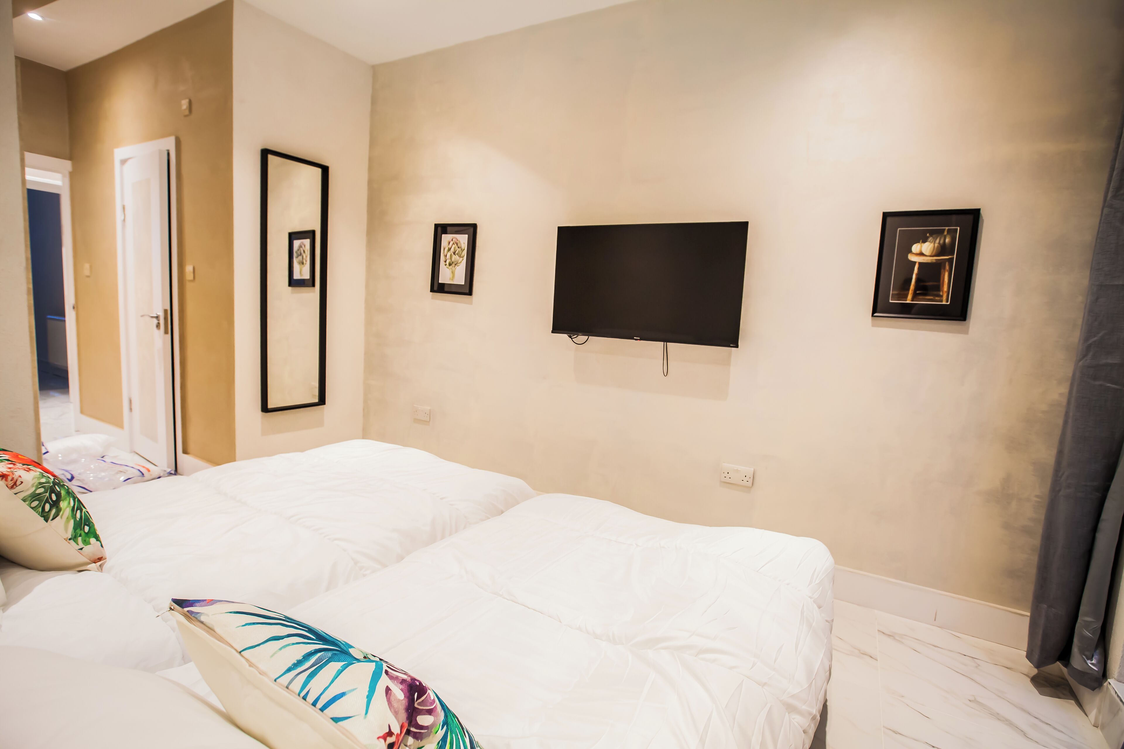 Ein Schlafzimmer mit einem Bett, einem an der Wand montierten Fernseher und einer Tür.