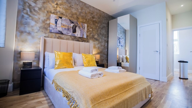 Une chambre à coucher moderne avec un grand lit, une tête de lit et une œuvre d’art accrochée au mur.