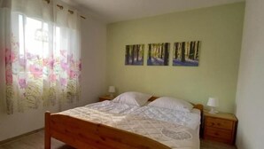 A bedroom with a wooden bed, a nightstand, and a wall with three framed pictures. - Ferienhaus Bernstein in Ruhiger Lage (Kalkhorst)