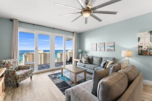 A spacious living room with a balcony overlooking the ocean, a ceiling fan, and a view of the sea. - Laketown Wharf 1306 | Pineapple Willy`s Gift Card, Panoramic Ocean Views, Private Balcony (Panama City Beach)