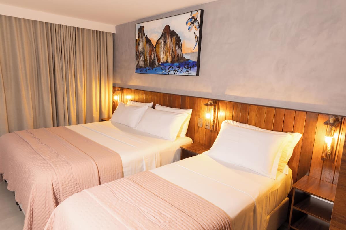 Hotellihuone, jossa on kaksi sänkyä, seinällä taulu ja sängyissä puiset päätyosat.