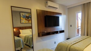 Ein Hotelzimmer mit zwei Betten, einem Wandfernseher, einem Gemälde und einer Klimaanlage.