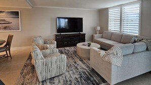 A living room with a sofa, armchair, and a flat-screen TV on a stand.