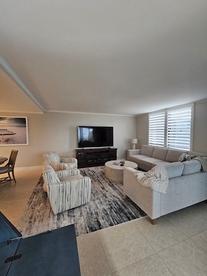 A living room with a sofa, armchair, and a flat-screen TV on a stand.