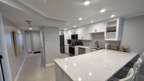 A modern kitchen with white cabinets, a large marble island, and stainless steel appliances. - Modern Condo! Beach Access, Shared Pools, and Activities! Gulf and Bay Club D409 (Siesta Key)
